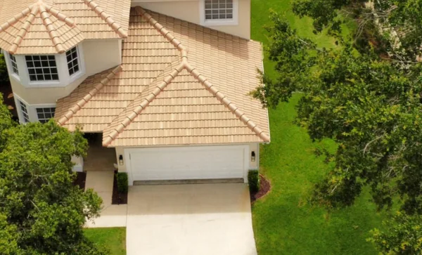 A two-story home's tan tile roof after a soft wash, seen from a drone