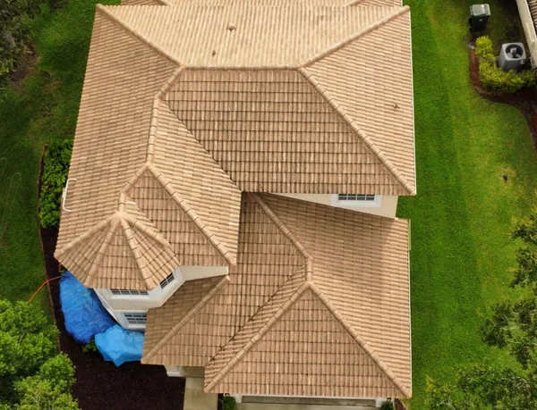 A tan tile roof before cleaning, dark with algae