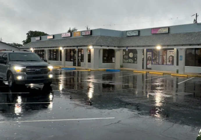 A plaza parking lot and storefronts after a commercial wash