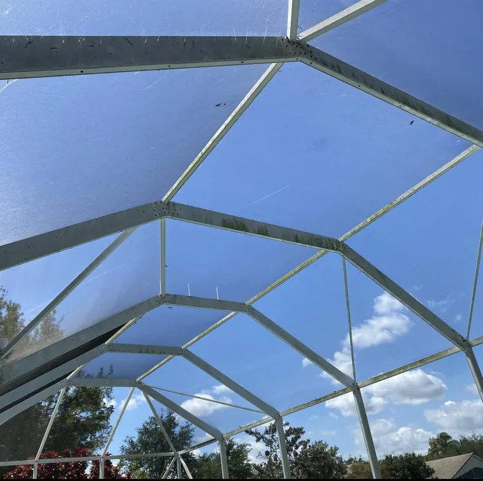 Looking up through a clean pool screen enclosure at blue sky